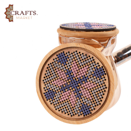 A glass coffee pot with a hand-embroidered wooden lid and a hand-embroidered wooden coaster