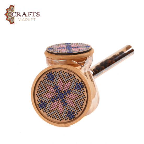 A glass coffee pot with a hand-embroidered wooden lid and a hand-embroidered wooden coaster